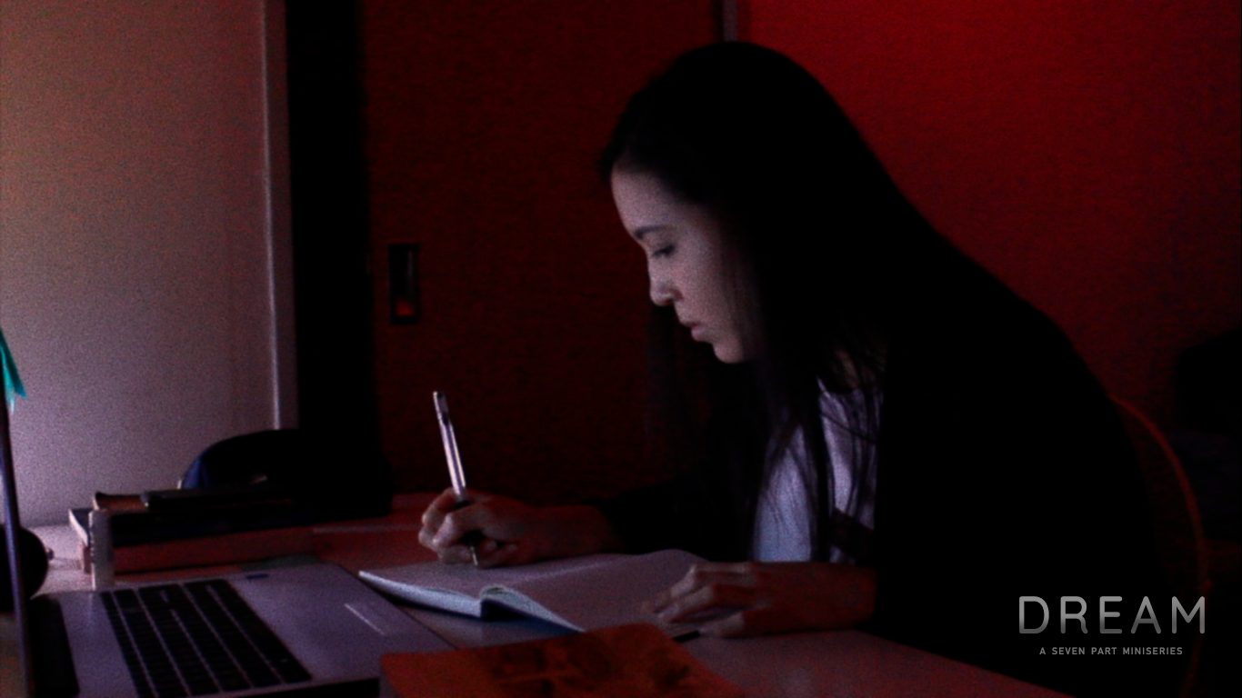 Una mujer escribiendo de noche en un cuarto iluminado de rojo